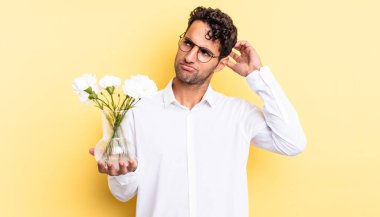 İspanyol yakışıklı adam mutlu bir şekilde gülümsüyor ve hayal kuruyor ya da şüphe ediyor. çiçek saksı konsepti