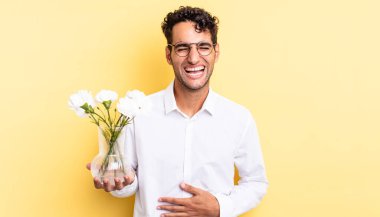 İspanyol yakışıklı bir adam komik bir şakaya yüksek sesle gülüyor. çiçek saksı konsepti