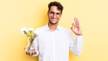 İspanyol yakışıklı adam kendini mutlu hissediyor, iyi bir jestle onaylıyor. çiçek saksı konsepti