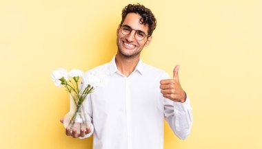 İspanyol yakışıklı adam kendini gururlu hissediyor, başparmağıyla olumlu gülümsüyor. çiçek saksı konsepti