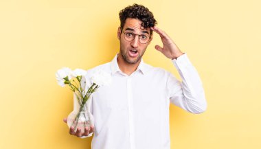 İspanyol yakışıklı adam mutlu, şaşkın ve şaşırmış görünüyor. çiçek saksı konsepti