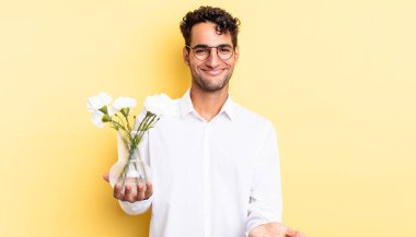 İspanyol yakışıklı adam mutlu bir şekilde gülümsüyor ve bir konsept sunuyor. çiçek saksı konsepti
