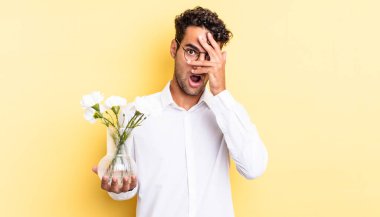 İspanyol yakışıklı adam şok olmuş, korkmuş ya da korkmuş görünüyor. Yüzü elle kapatılmış. çiçek saksı konsepti