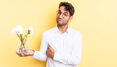 İspanyol yakışıklı adam omuz silkiyor, kafası karışık ve kararsız. çiçek saksı konsepti