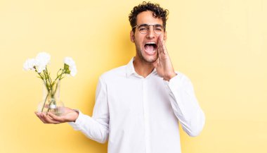 İspanyol yakışıklı adam kendini mutlu hissediyor, elleri ağızının yanında bağırıyor. çiçek saksı konsepti