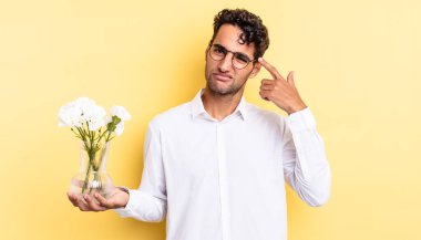 İspanyol yakışıklı adam kafası karışık ve şaşkın hissediyor, senin deli olduğunu gösteriyor. çiçek saksı konsepti