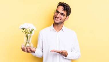 İspanyol yakışıklı adam neşeyle gülümsüyor, mutlu hissediyor ve bir konsept gösteriyor. çiçek saksı konsepti