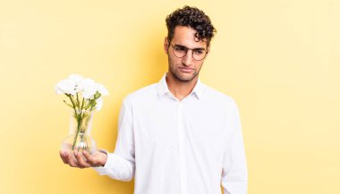 Hispanik yakışıklı adam üzgün, üzgün ya da kızgın hissediyor ve yana bakıyor. çiçek saksı konsepti