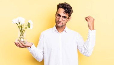 İspanyol yakışıklı adam kapiş ya da para hareketi yapıyor, sana ödemeni söylüyor. çiçek saksı konsepti