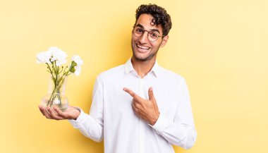 İspanyol yakışıklı adam heyecanlı ve şaşırmış görünüyor. çiçek saksı konsepti