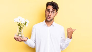İspanyol yakışıklı adam, inançsızlıktan şaşkın şaşkın bakıyor. çiçek saksı konsepti