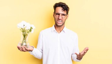 İspanyol yakışıklı adam sinirli, sinirli ve sinirli görünüyor. çiçek saksı konsepti