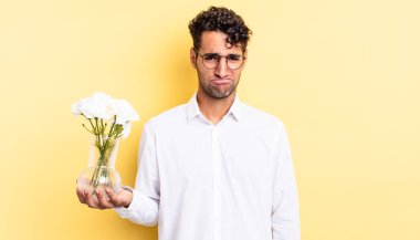 Hispanik yakışıklı adam üzgün ve mızmız, mutsuz bir bakışla ağlıyor. çiçek saksı konsepti