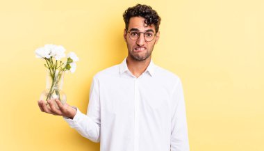 İspanyol yakışıklı adam kafası karışmış ve şaşkın görünüyor. çiçek saksı konsepti