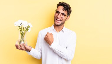 İspanyol yakışıklı adam kendini mutlu hissediyor ve bir meydan okumayla yüzleşiyor ya da kutluyor. çiçek saksı konsepti