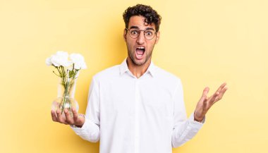 İspanyol yakışıklı adam son derece şaşırmış ve şok olmuş hissediyor. çiçek saksı konsepti