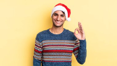 İspanyol yakışıklı adam kendini mutlu hissediyor, iyi bir jestle onaylıyor. Noel konsepti