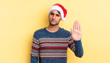 İspanyol yakışıklı adam ciddi görünüyor. Avuç içi gösteriyor. Durdurma hareketi yapıyor. Noel konsepti