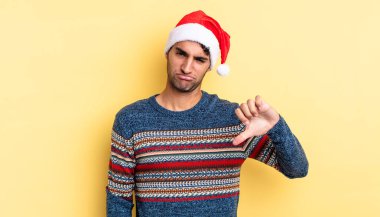 Latin asıllı yakışıklı adam kızgın, baş parmağını kaldırıyor. Noel konsepti