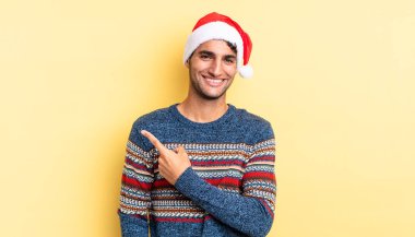 İspanyol yakışıklı adam neşeyle gülümsüyor, mutlu hissediyor ve bir tarafı işaret ediyor. Noel konsepti