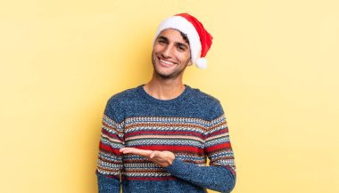 İspanyol yakışıklı adam neşeyle gülümsüyor, mutlu hissediyor ve bir konsept gösteriyor. Noel konsepti