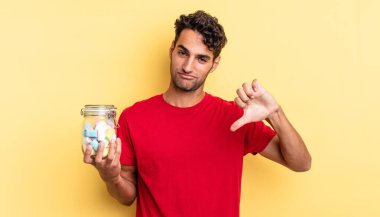 Latin asıllı yakışıklı adam kızgın, baş parmağını kaldırıyor. şeker konsepti