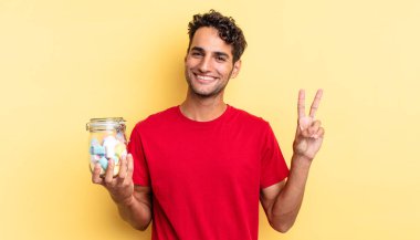 İspanyol yakışıklı adam gülümsüyor ve mutlu görünüyor, zafer ya da barış işareti yapıyor. şeker konsepti