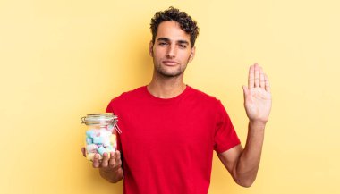 İspanyol yakışıklı adam ciddi görünüyor. Avuç içi gösteriyor. Durdurma hareketi yapıyor. şeker konsepti