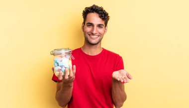 İspanyol yakışıklı adam mutlu bir şekilde gülümsüyor ve bir konsept sunuyor. şeker konsepti