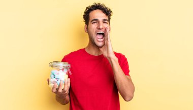 İspanyol yakışıklı adam kendini mutlu hissediyor, elleri ağızının yanında bağırıyor. şeker konsepti