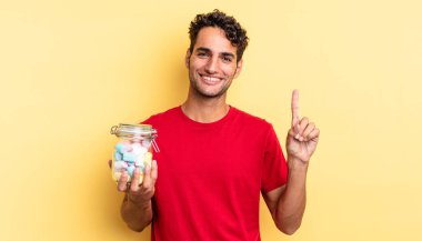 İspanyol yakışıklı adam gülümsüyor ve arkadaş canlısı görünüyor, bir numarayı gösteriyor. şeker konsepti