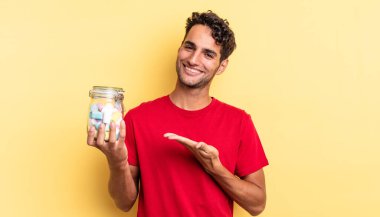 İspanyol yakışıklı adam neşeyle gülümsüyor, mutlu hissediyor ve bir konsept gösteriyor. şeker konsepti