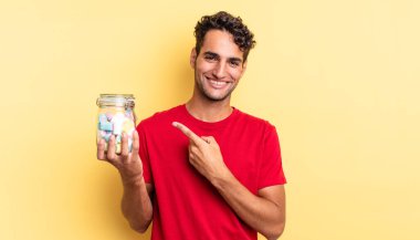 İspanyol yakışıklı adam neşeyle gülümsüyor, mutlu hissediyor ve bir tarafı işaret ediyor. şeker konsepti