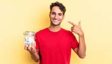 İspanyol yakışıklı adam kendine güvenerek gülüyor ve kendi gülüşüne işaret ediyor. şeker konsepti