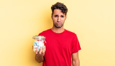 Hispanik yakışıklı adam üzgün ve mızmız, mutsuz bir bakışla ağlıyor. şeker konsepti