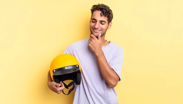 ヒスパニックハンサムな男は幸せな自信を持って笑顔で顎に手で表現します バイクヘルメットのコンセプト — ストック写真