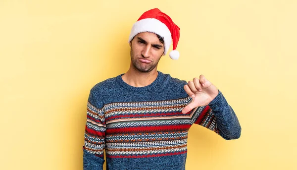 Latin asıllı yakışıklı adam kızgın, baş parmağını kaldırıyor. Noel konsepti