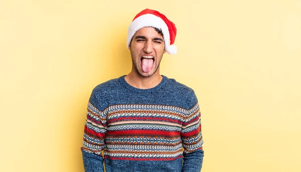 陽気で反抗的な態度を持つパニックハンサムな男冗談と舌を突き出す クリスマスのコンセプト — ストック写真