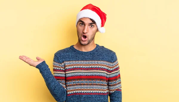 ヒスパニックハンサムな男が驚いてショックを受け顎が物を持って落下した クリスマスのコンセプト — ストック写真