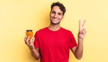 İspanyol yakışıklı adam gülümsüyor ve mutlu görünüyor, zafer ya da barış işareti yapıyor. Şeftali reçeli