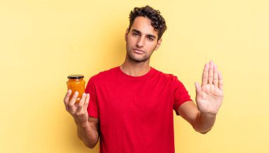 İspanyol yakışıklı adam ciddi görünüyor. Avuç içi gösteriyor. Durdurma hareketi yapıyor. Şeftali reçeli