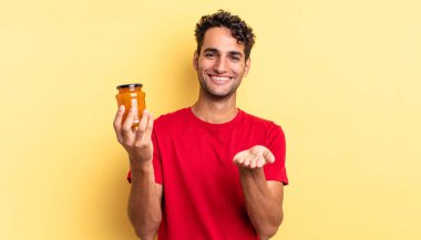 İspanyol yakışıklı adam mutlu bir şekilde gülümsüyor ve bir konsept sunuyor. Şeftali reçeli