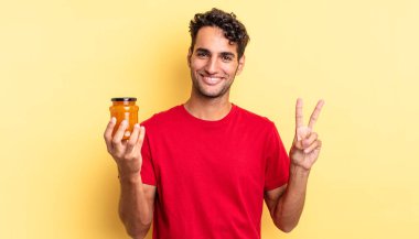 İspanyol yakışıklı adam gülümsüyor ve arkadaş canlısı görünüyor, iki numarayı gösteriyor. Şeftali reçeli