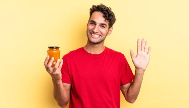 İspanyol yakışıklı adam mutlu bir şekilde gülümsüyor, el sallıyor, seni selamlıyor ve selamlıyor. Şeftali reçeli