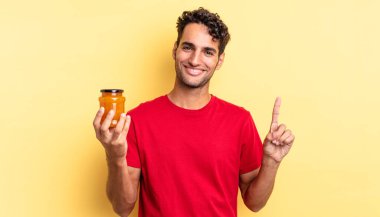 İspanyol yakışıklı adam gülümsüyor ve arkadaş canlısı görünüyor, bir numarayı gösteriyor. Şeftali reçeli