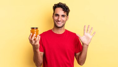 İspanyol yakışıklı adam gülümsüyor ve arkadaş canlısı görünüyor, beş numarayı gösteriyor. Şeftali reçeli