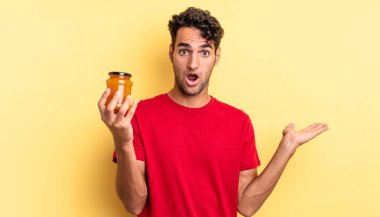 İspanyol yakışıklı adam şaşırmış ve şok olmuş görünüyor. Çenesi düşmüş ve elinde bir nesne var. Şeftali reçeli