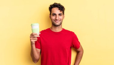 İspanyol yakışıklı adam mutlu bir şekilde gülümsüyor, eli kalçasında ve kendinden emin. kahve konseptini kaldır.