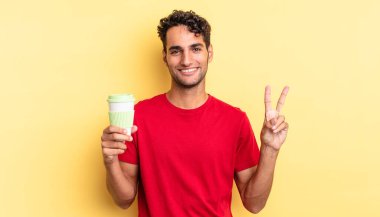 İspanyol yakışıklı adam gülümsüyor ve arkadaş canlısı görünüyor, iki numarayı gösteriyor. kahve konseptini kaldır.