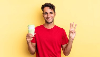 İspanyol yakışıklı adam gülümsüyor ve arkadaş canlısı görünüyor, üç numarayı gösteriyor. kahve konseptini kaldır.